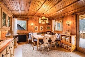 L’intérieur d’un chalet en bois comprend une table à manger, des chaises, un canapé et une bibliothèque intégrée.