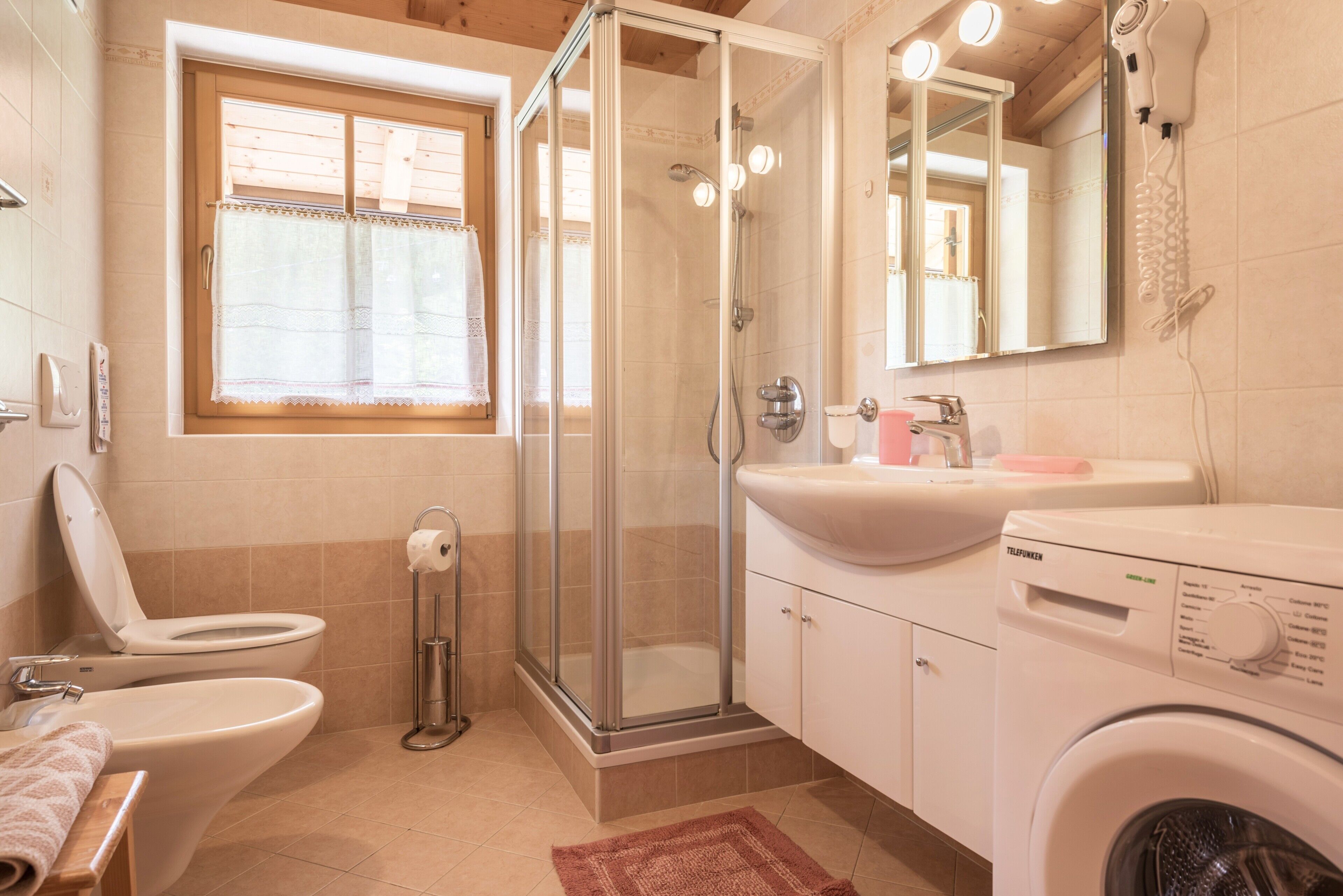 Ein Badezimmer mit Toilette, Dusche, Waschbecken und Waschmaschine.