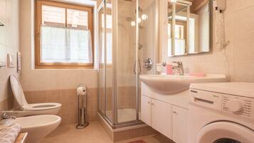 Ein Badezimmer mit Toilette, Dusche, Waschbecken und Waschmaschine.