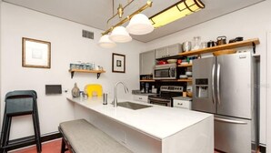 A modern kitchen with a central island, stainless steel appliances, and a pendant light fixture. - Close to Downtown, LECOM Field, AMI Beaches and more (Bradenton)