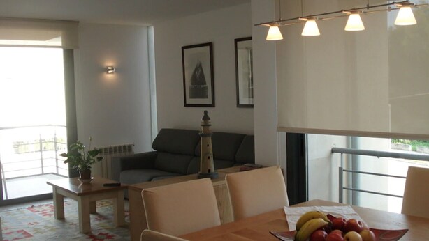 A modern living room with a dining table, a sofa, and a small table with a potted plant. - Holiday Apartment Apartamento Llenaire with Pool, Wi-Fi, A/C, Garden, Terrace & Balcony; Parking Available (Pollensa)