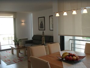 A modern living room with a dining table, a sofa, and a small table with a potted plant.