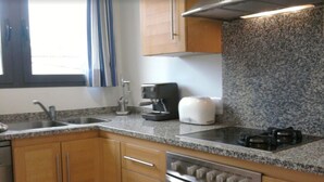 A kitchen with granite countertops, stainless steel appliances, wooden cabinets, and a window with curtains. - Holiday Apartment Apartamento Llenaire with Pool, Wi-Fi, A/C, Garden, Terrace & Balcony; Parking Available (Pollensa)