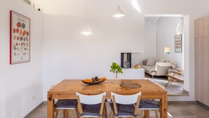 Un comedor con una mesa de madera, dos sillas, un florero con planta y un frutero.