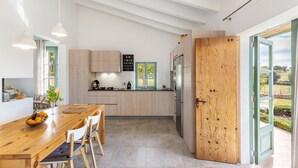 Una cocina moderna con armarios de madera, una mesa de comedor con sillas y vistas a través de una puerta abierta.