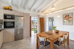 Eine moderne Küche mit Edelstahlgeräten, einem Holztisch und Blick ins Freie.