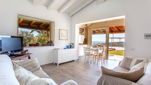 Una sala de estar moderna con televisor, sofá y comedor con vistas.