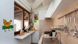 Una cocina con lavamanos, estufa y utensilios colgando.