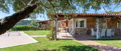 A stone house with a patio, outdoor furniture, and a view of the surrounding landscape.