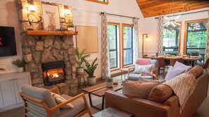 Una sala de estar acogedora con chimenea de piedra, asientos cómodos y ventanas amplias.