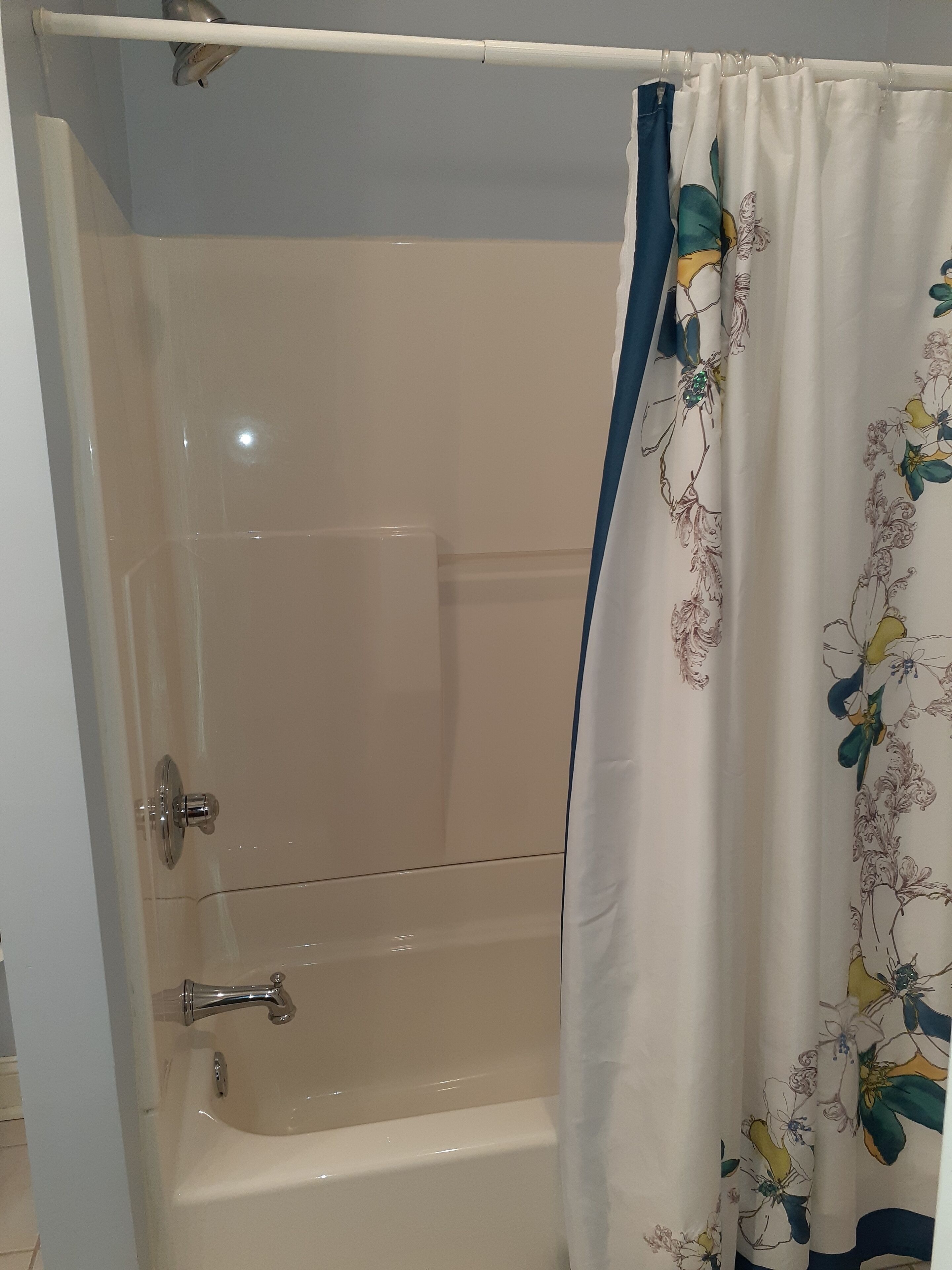 Una bañera con cortina de ducha estampada con motivos florales.