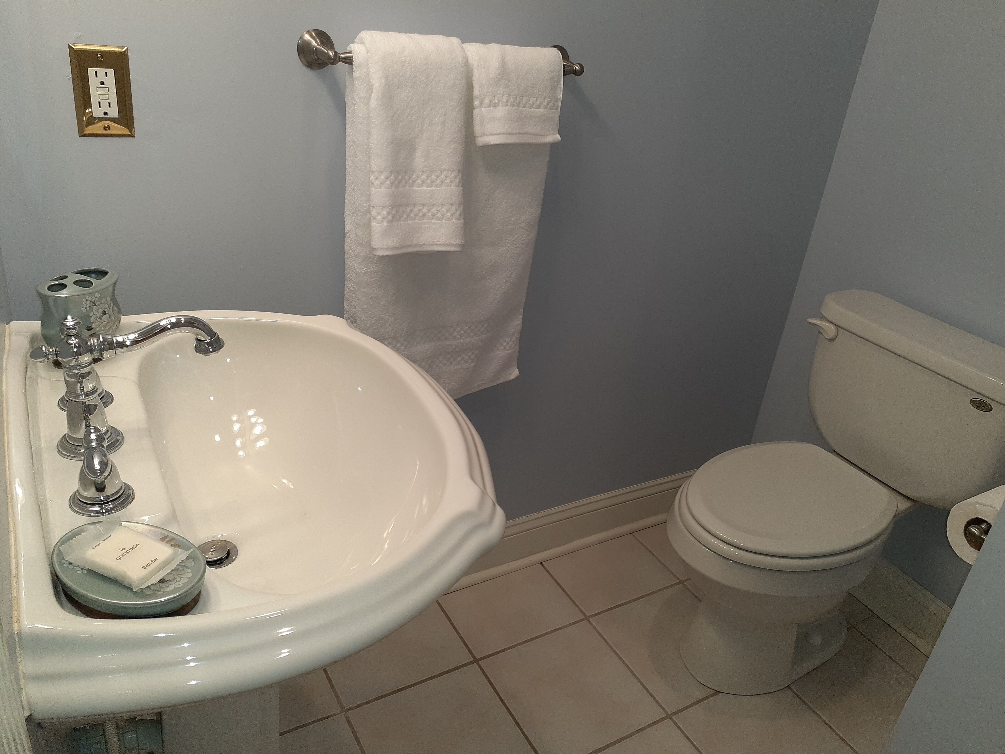 Une salle de bain avec un lavabo blanc, des toilettes et un porte-serviettes.