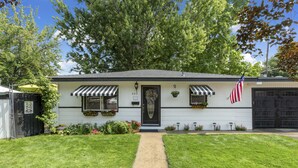 A single-story house with a front door, two windows with awnings, a small front porch, and an American flag. - ENJOY THE HISTORY, NOSTALGIA AND CULTURE OF OLD TOWN MERIDIAN (Meridian)
