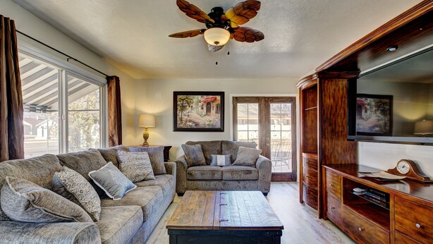 A living room with a sectional sofa, a coffee table, a wooden cabinet, and a ceiling fan. - ENJOY THE HISTORY, NOSTALGIA AND CULTURE OF OLD TOWN MERIDIAN (Meridian)