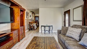 A living room with a wooden entertainment center, a sofa with patterned cushions, a glass coffee table, and a ceiling fan. - ENJOY THE HISTORY, NOSTALGIA AND CULTURE OF OLD TOWN MERIDIAN (Meridian)