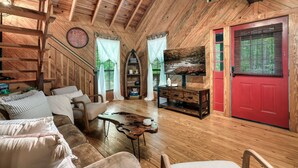 Un interior de cabaña acogedor con paredes de madera, una puerta roja y una chimenea.