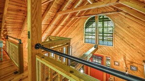 Un interior de madera con techo alto, una escalera y un amplio ventanal de arco.