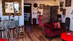 A cozy living room with a wooden floor, a red sofa, a red ottoman, and a ceiling fan. - The Barn, mini petting zoo mid term 1-6 month stays  (Warner Springs)