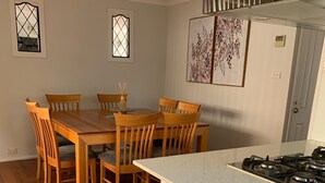 Une cuisine moderne avec un îlot central, une table à manger en bois et des chaises.