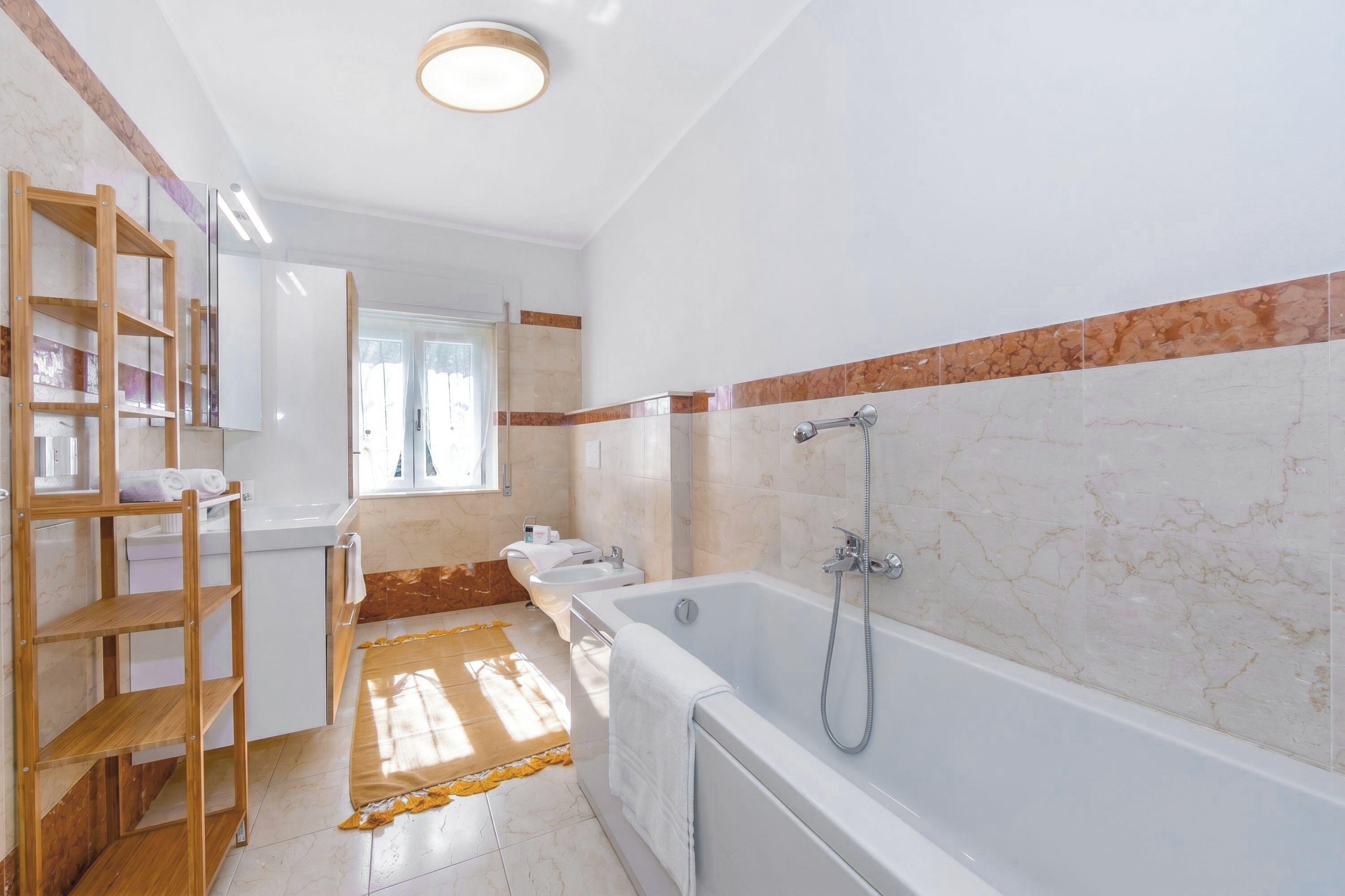 A bathroom with a bathtub, a wooden shelf, a window, and a towel rack.