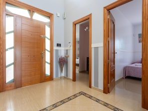A hallway with wooden doors, a tiled floor, and a vase with flowers.