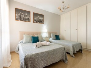 Een hotelkamer met twee bedden, een nachtkastje, een lamp en een kledingkast.