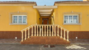 Un bâtiment à deux étages doté d’une entrée centrale, d’un escalier avec une balustrade et de deux fenêtres ornées de barreaux en fer décoratifs.