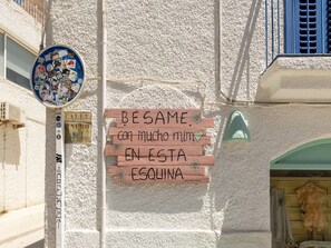 A building facade with a sign that reads 'BÉGAME con mucho miento EN ESTA ESQUINA' and a circular sign with various stickers. - Holiday Home with Pool (Venta del Pobre)