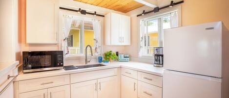 A kitchen with white cabinets, a microwave, a refrigerator, and a coffee maker.