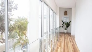 Un intérieur moderne avec une balustrade en verre, un plancher en bois et des plantes en pot.