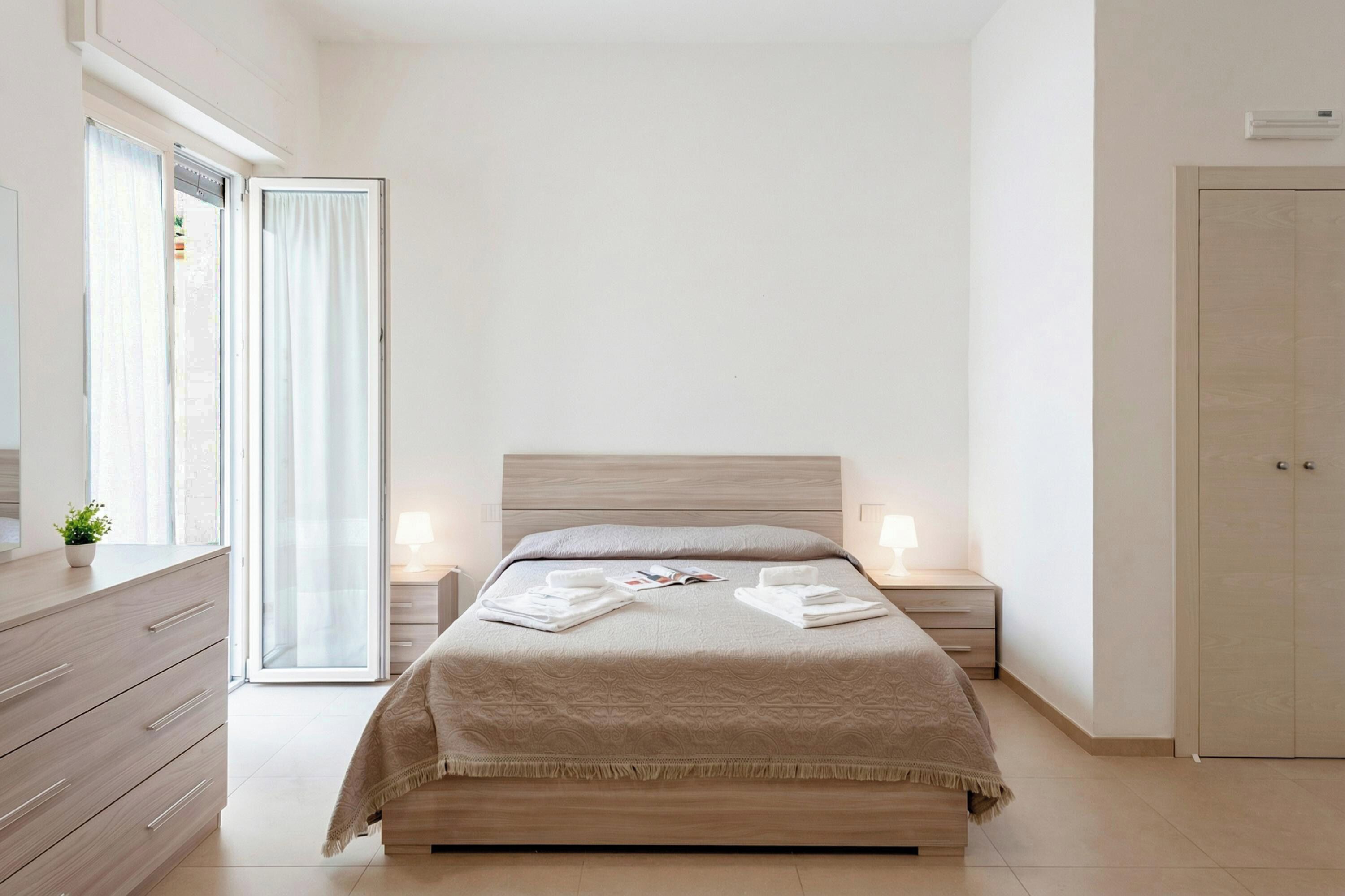 Una camera da letto con un letto, comodini, una cassettiera, un armadio e una porta scorrevole in vetro.