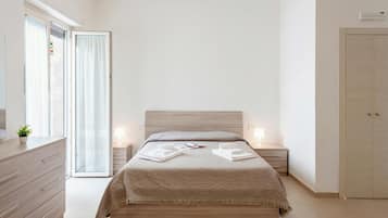 Un dormitorio con cama, mesitas de noche, cómoda, armario y puerta corrediza de cristal.
