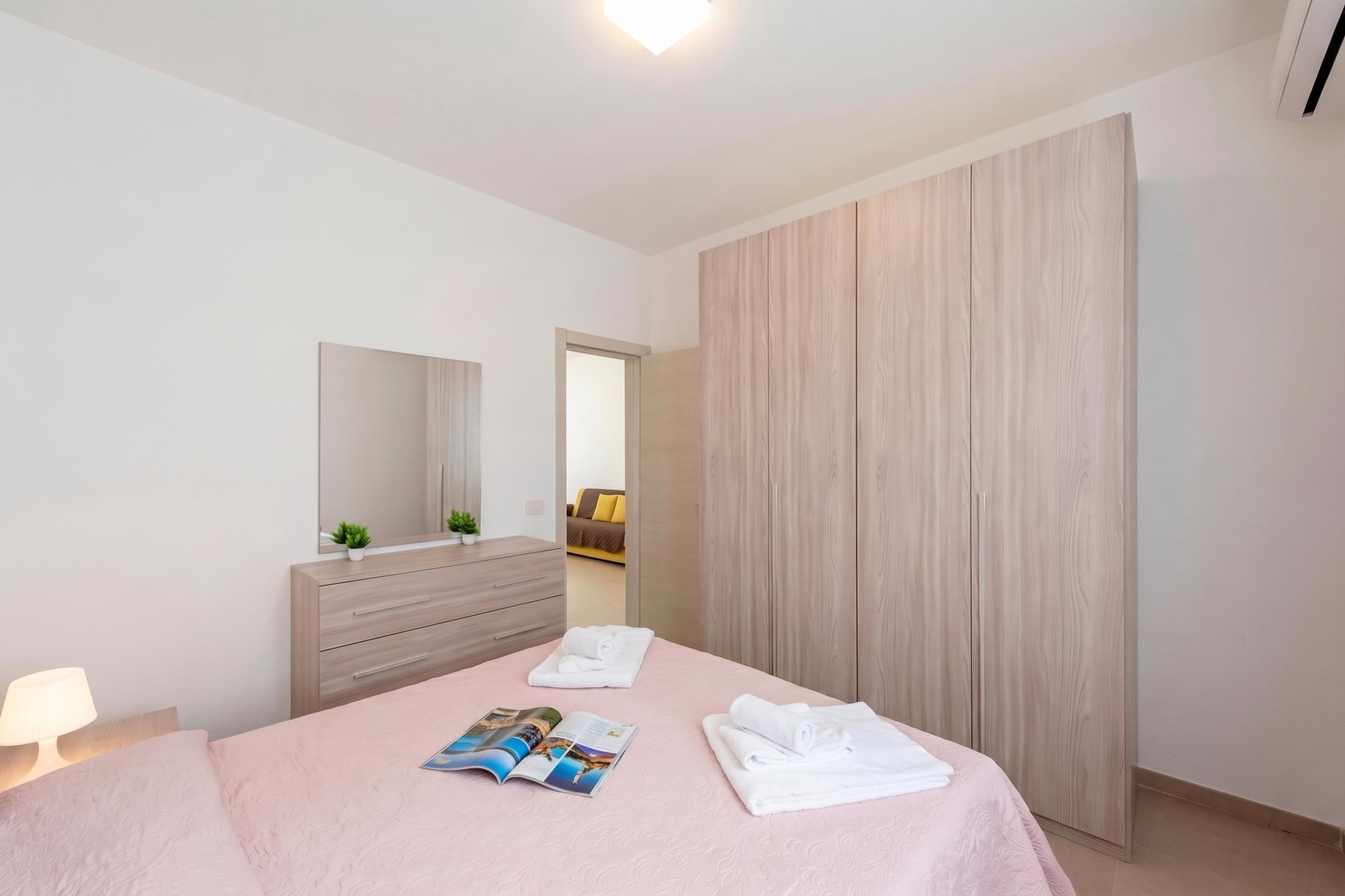 Un dormitorio moderno con cama, mesita de noche, espejo y armario.