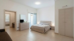 A bedroom with a bed, a dresser, a TV, a desk, and a wardrobe. - Suite Ondina Viareggio Apartments (Viareggio)