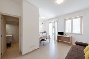 A modern apartment with a dining area, a TV, and a bed.