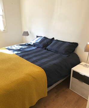 Une chambre à coucher avec un lit, une table de chevet et une lampe.