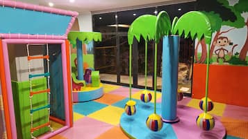 A children's play area with colorful mats, a climbing structure, and hanging balls.