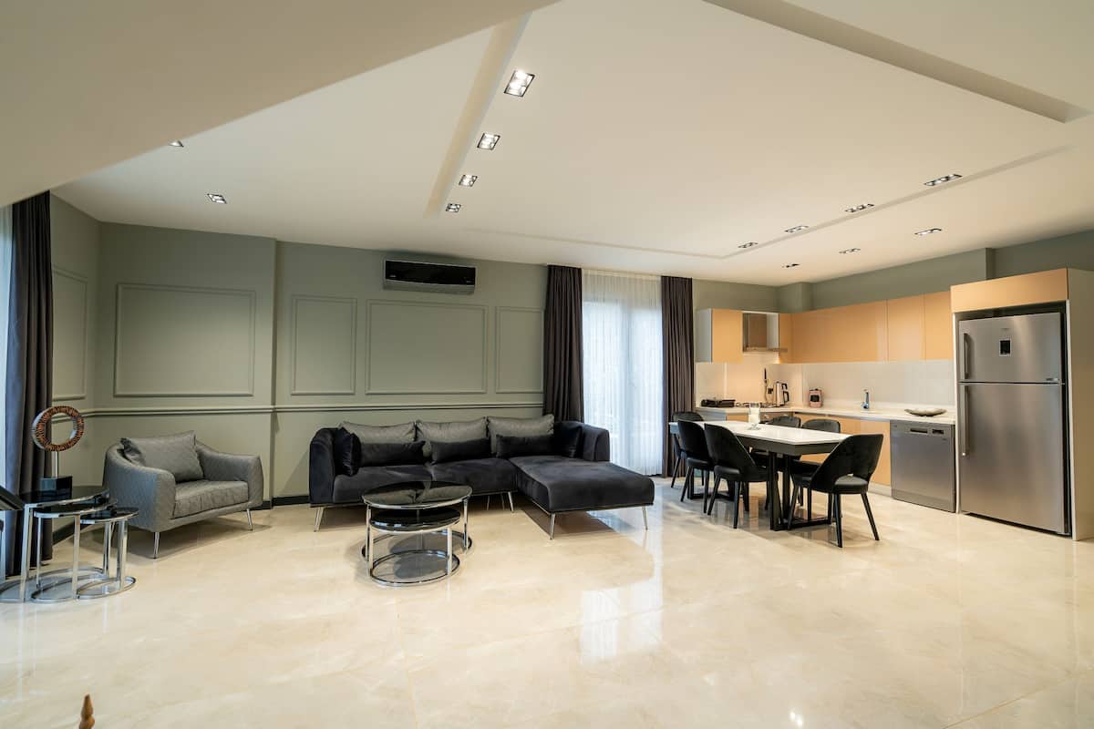 A modern living room with a sectional sofa, a coffee table, and a dining area with chairs and a table.