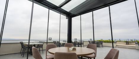 A modern meeting room with a glass ceiling, large windows, and a view of the sea.
