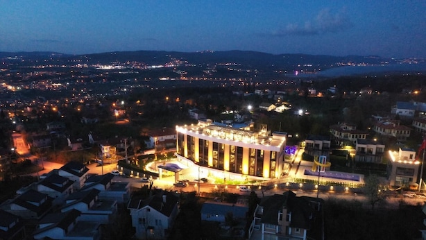 A modern building with a central atrium, surrounded by residential areas and a distant cityscape. - Aileena Hotel & Villas (Kartepe)