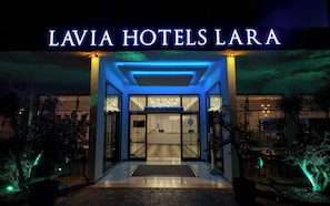 L'entrée de l'hôtel Lavia Hotels Lara se distingue par son design moderne, ses portes en verre et sa façade bien éclairée.