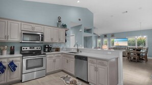 A modern kitchen with white cabinetry, stainless steel appliances, and a large island.