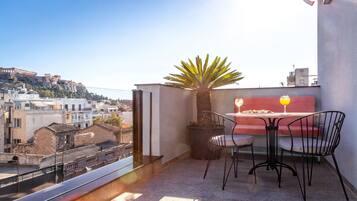 A balcony with a table and chairs, a potted plant, and a view of the cityscape.