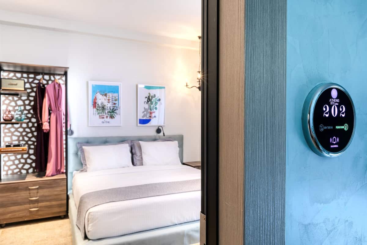 A hotel room with a bed, a wardrobe, and a digital thermostat displaying room temperature.
