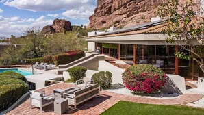 Una casa moderna con piscina, mobiliario de exterior y vistas a una montaña rocosa.