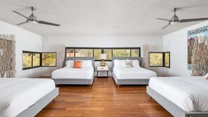 Habitación de hotel con dos camas, una mesita de noche, una lámpara y ventana con vista a árboles.