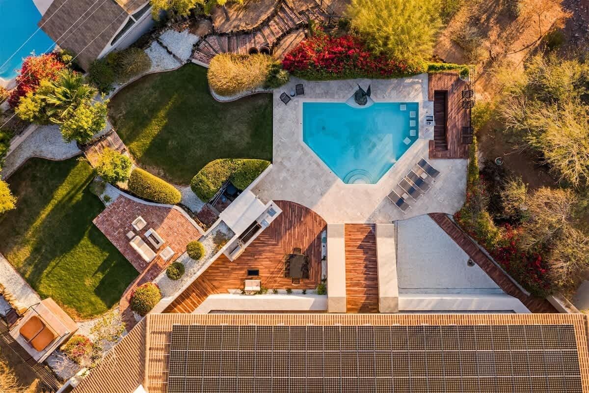 An aerial view of a modern building with a swimming pool, outdoor seating, and landscaped gardens.