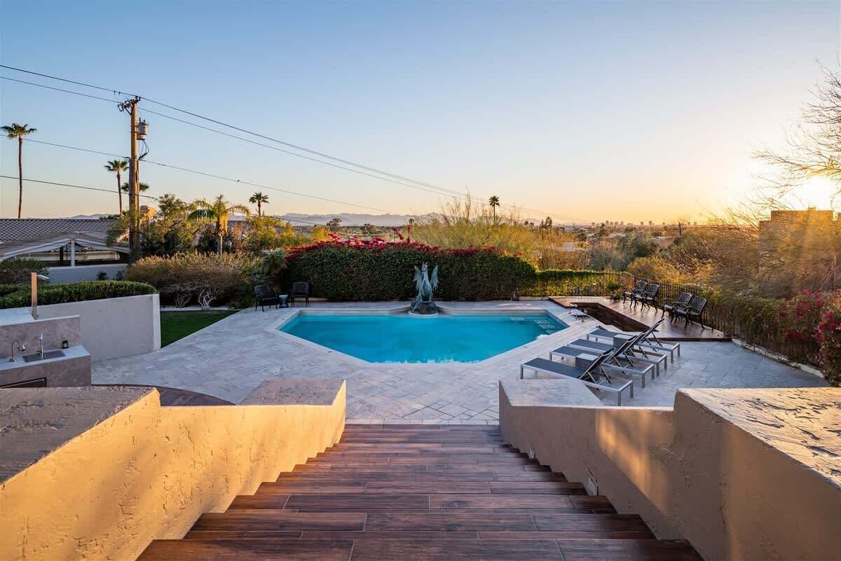 A swimming pool with a fountain, surrounded by a landscaped garden and a staircase leading up.