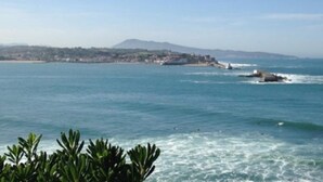 A coastal view with a mountain in the distance, calm sea, and a rocky outcrop. - Cozy Ground Floor Apartment Near Erromardie Beach, Terrace & Parking (Saint-Jean-de-Luz)