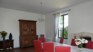A dining room with a large wooden cabinet, a chandelier, and a fireplace. - Charming Cottage Near Le Mans: Garden, Terrace, 4 Bedrooms, 3 Bathrooms, Wi-Fi, Family Friendly (Écommoy)